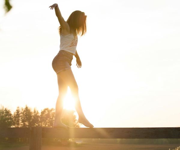 Person feeling energetic and stretching outdoors during sunrise.